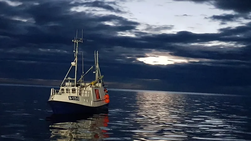 En enslig fiskebåt alene på åpent hav i skumring